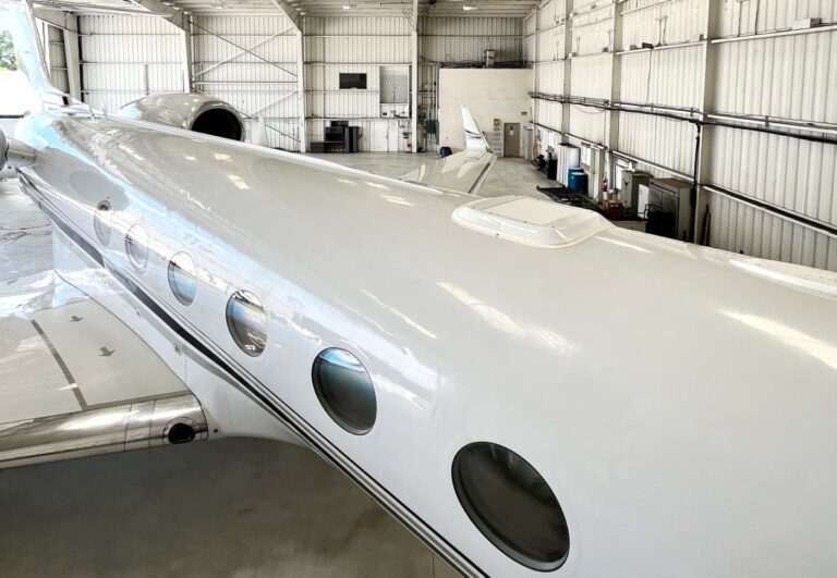 Private jet inside a spacious hangar, highlighting its sleek design and windows.