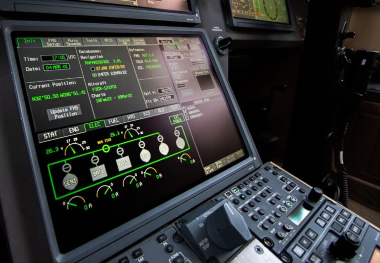 Close-up of an aircraft cockpit display showing navigation data and system information on multiple screens with control buttons.