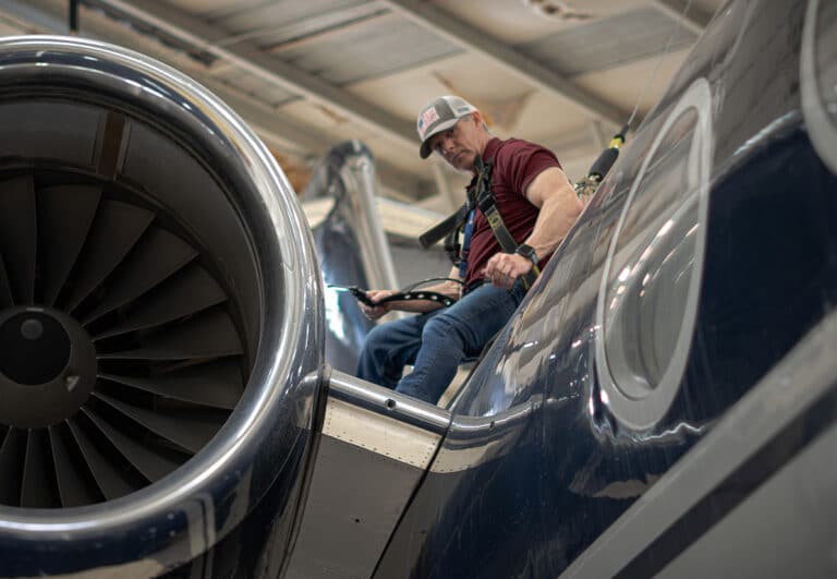 Business Jet Maintenance Technician on top of a Gulfstream looking down.