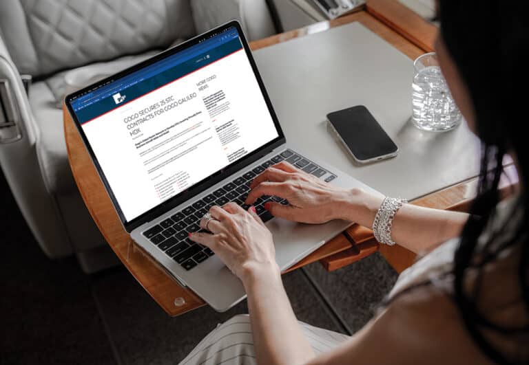 A passenger on a private jet on their mac viewing the Gogo website news