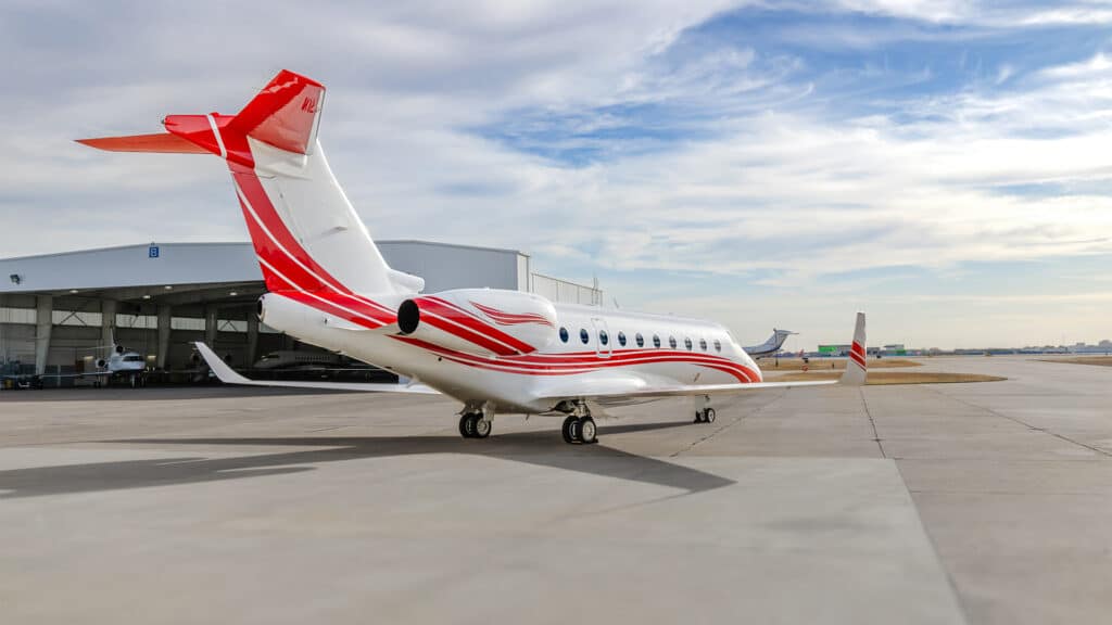 Exterior tail view of a Gulfstream G280 with an open aircraft hangar in the background.