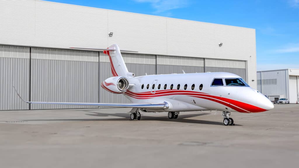 Exterior tail view of a Gulfstream G280 with an open aircraft hangar in the background.