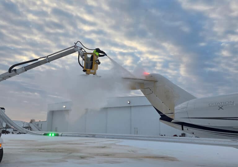 FBO team member performing aircraft de-icing service during a winter storm.