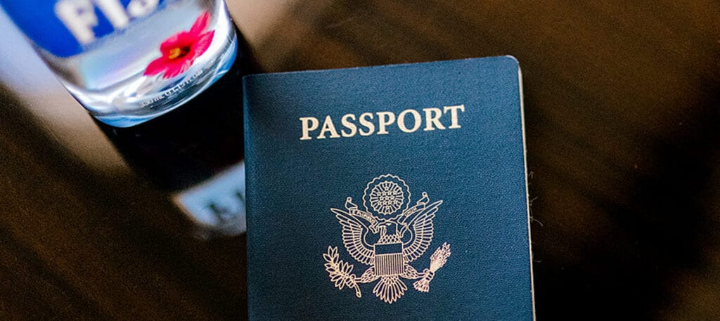 A passport on a highly polished wooden table next to a bottle of water prepared for customs at KDAL for the FIFA World Cup