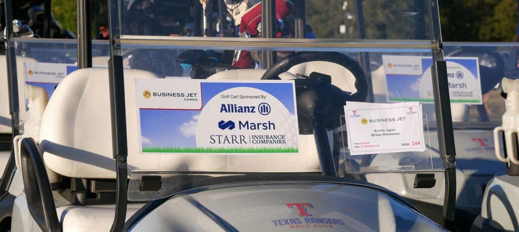 Golf Carts lined up and ready for the Business Jet Charity Golf Tournament with Sponsor information on the window