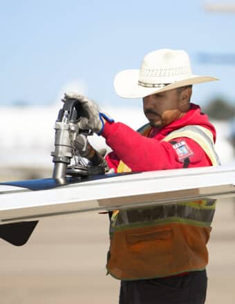 Dallas Love Field Business Jet FBO Line Service Technician fueling an aircraft while wearing a cowboy hat