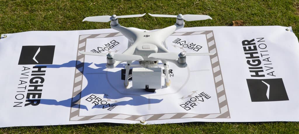 A drone sitting on a branded launch pad about to take off and carry a golf ball to the green