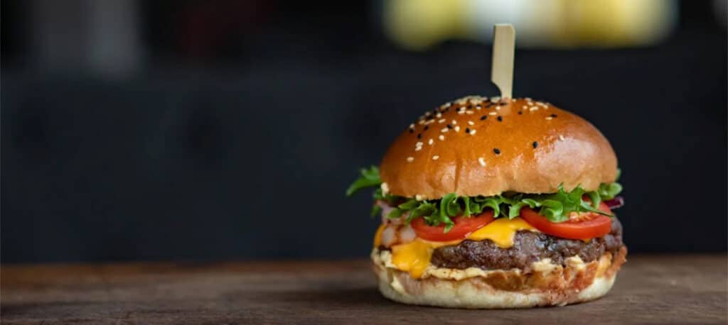 A delicious cheeseburger sitting on a butcher block