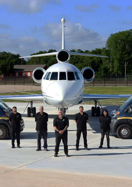 Business Jet AOG team posed in front of a Falcon 900EX and two AOG vans